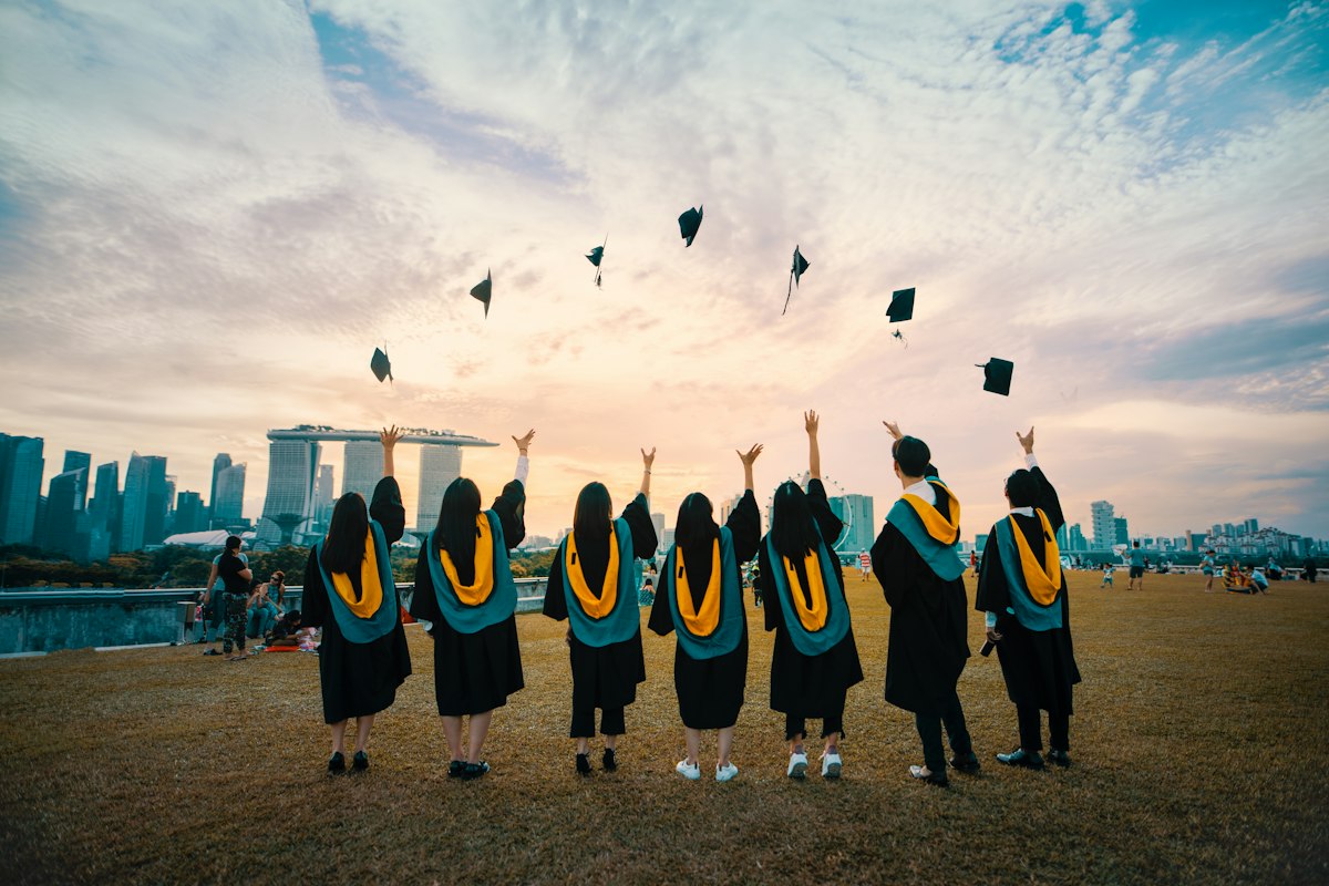 Graduates throwing caps at sunset